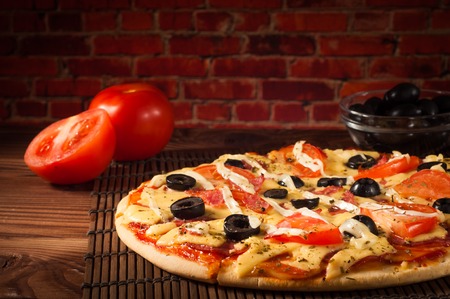Hot pizza slice with melting cheese on a rustic wooden tableの写真素材