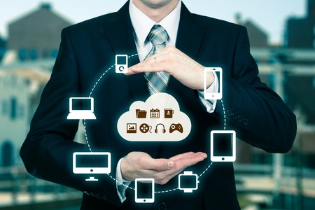 Businessman touching a cloud connected to many objects on a virtual screen, concept about internet of things.の写真素材