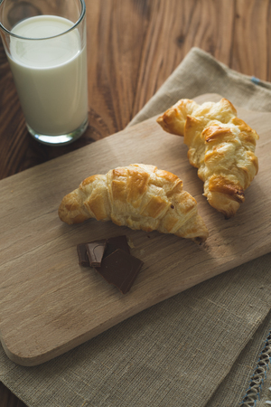 freshly baked croissants on a wooden cutting board with a glass of milk. Tasty breakfastの写真素材