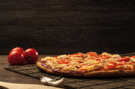 Hot pizza slice with melting cheese on a rustic wooden tableの写真素材