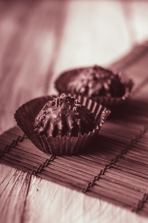 Chocolate chip muffin in brown wax paper. Unwrapped. Cocoa powder in the backgroundの写真素材