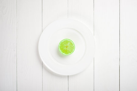 Fresh lime in a plate on wooden background. Half of lemon