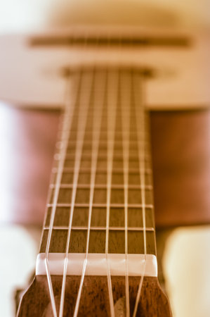 Part of an acoustic guitar on a grey background.