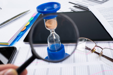 Hourglass. Businessman working in the office in the background. Concept time is money.