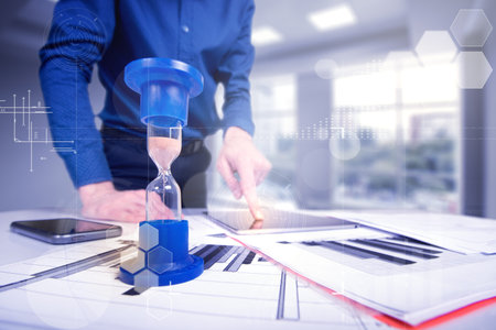 Hourglass. Businessman working in the office in the background. Concept time is money.
