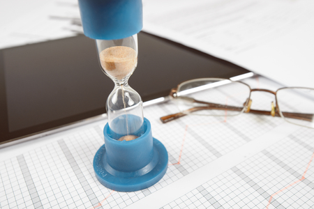 Hourglass. Businessman working in the office in the background. Concept time is money.の写真素材