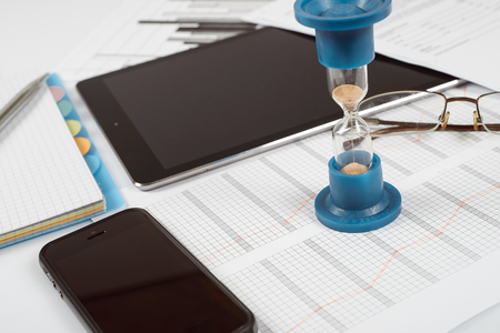 Hourglass. Businessman working in the office in the background. Concept time is money.の写真素材