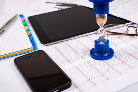 Hourglass. Businessman working in the office in the background. Concept time is money.の写真素材