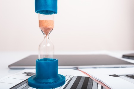 Hourglass. Businessman working in the office in the background. Concept time is money.の写真素材