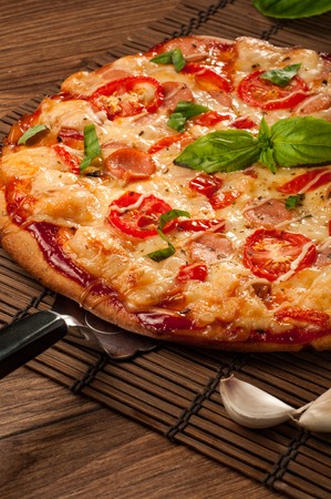 Hot pizza slice with melting cheese on a rustic wooden tableの写真素材