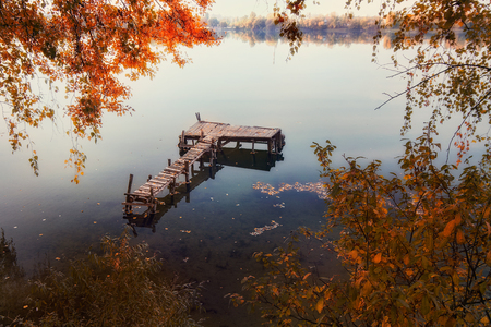 Autumn foliage and fog lake in morning with boat dock.の写真素材
