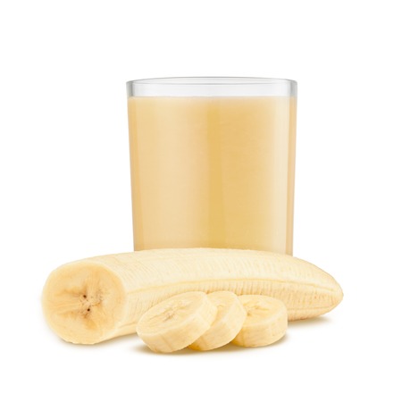 Fresh banana shake in a glass and banana pieces isolated on white backgroundの写真素材