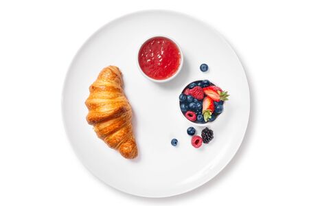 croissant with chocolate on a white plate with fresh fruits and jamの写真素材