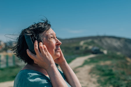 portrait adult woman listens to music in headphones in summer, spring against the backdrop of...