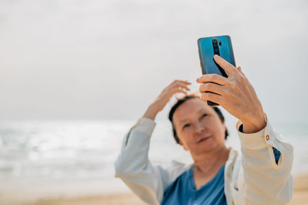 an adult woman on the beach near the ocean in the spring at a picnic takes a selfie, talks a video...