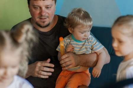 father with many children has fun playing with his small children at home, blowing soap bubblesの写真素材