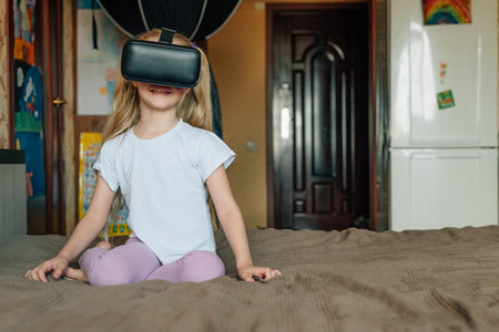 child girl at home in virtual reality VR glasses watching video, playing games. modern children are well versed in technological innovations. generation alphaの写真素材