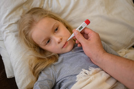 dad measures the temperature of his child, thinking that he is sick. The father suspects that his...