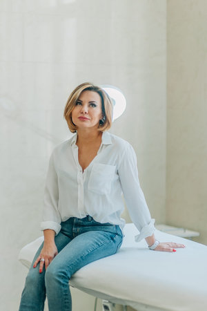 confident adult woman sitting on a couch in the office of a cosmetologist doctor.