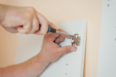 man collects furniture. A man works with a Phillips screwdriver: attaches a door hingeの写真素材