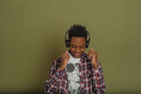 Young african american guy listens to music on headphones and dances on a green backgroundの写真素材