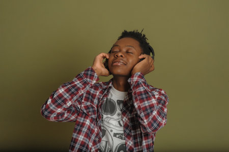 Young african american guy listens to music on headphones and dances on a green backgroundの写真素材
