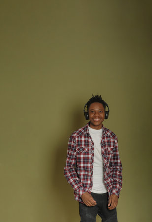 Young african american guy listens to music on headphones and dances on a green backgroundの写真素材