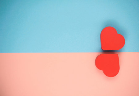 two red hearts on blue and pink backgroundの写真素材