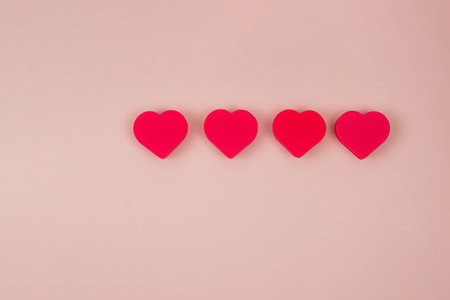 Four red hearts on a pink background