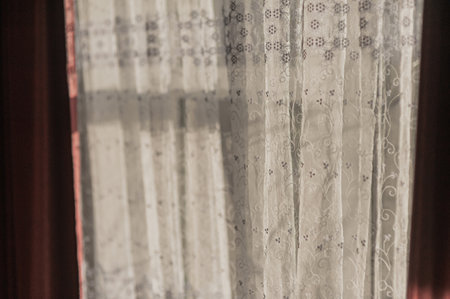 white curtains on the window in the sunbeams close-upの写真素材