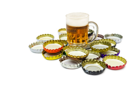 Metal beer bottle caps crown the group isolated on white. On top is a decorative beer mug. Conceptual image of alcohol consumption.の写真素材