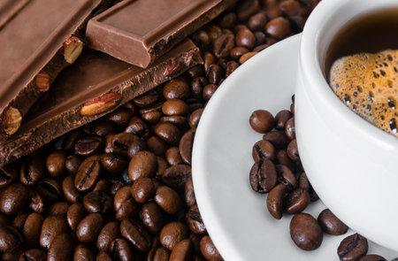 Cup of coffee and chocolate on coffee beans background, close upの写真素材