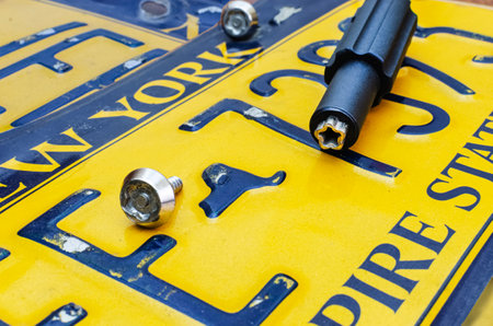 Close-up of removing an old yellow car sign. Special screws and keyの写真素材