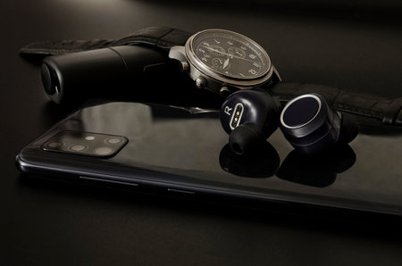 Gadgets on a dark background: a watch, headphones, a tobacco heater and a phone.の写真素材