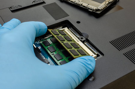 Computer service`s hand extracts internal memory from the inside of the laptop