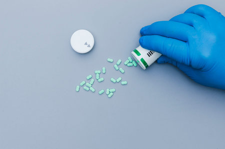 Close-up of the hands of a medical worker or pharmacist in blue latex protective gloves pouring...
