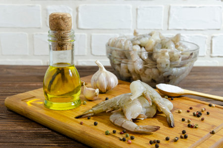 Raw shrimp on a cutting board with olive oil, spices and garlic.の写真素材