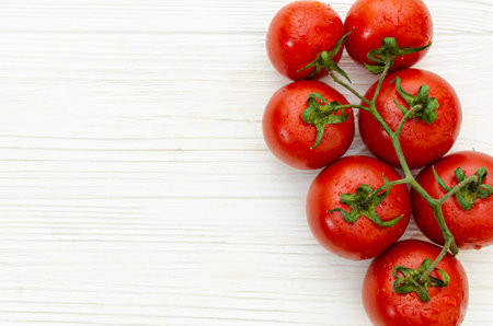 Top view of a branch of ripe tasty tomatoes on a white wooden surfaceの写真素材