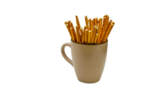 A close-up of a collection of golden brown pretzel sticks neatly arranged inside a beige ceramic mug.の写真素材
