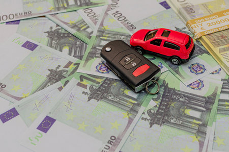 Car key euro money and red toy car, car insurance, sale or rentの写真素材