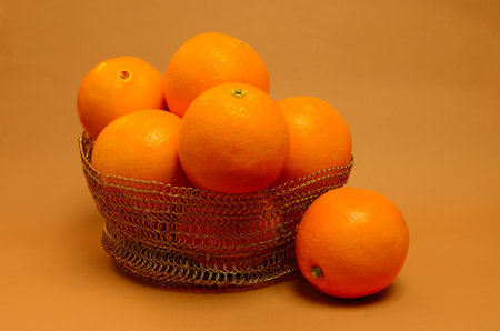 Close-up of an orange in a basket whole on an orange backgroundの写真素材