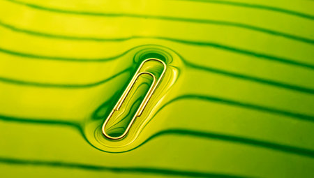 Abstract. Paper clip floating on the surface of water. Green backlightの写真素材