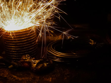 a dramatic close-up of bright sparks flying from a metal object in a dark industrial setting, surrounded by coiled cables and rugged tools, capturing the intensity of heavy-duty work.の写真素材