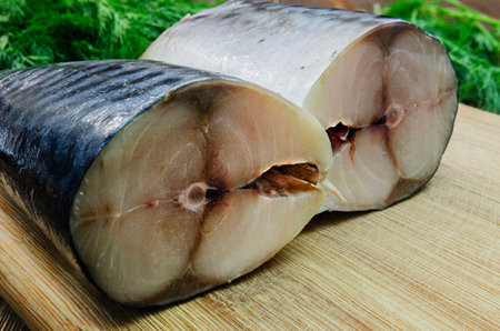 Close-up of freshly cut mackerel slices on a wooden cutting board, showing the fish's shiny skin and tender flesh.の写真素材