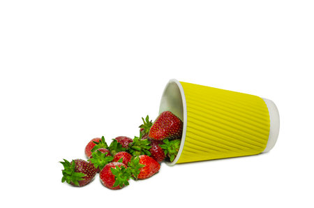 Fresh, ripe strawberries spill out of a vibrant yellow ripple cup, isolated on a clean white background.の写真素材