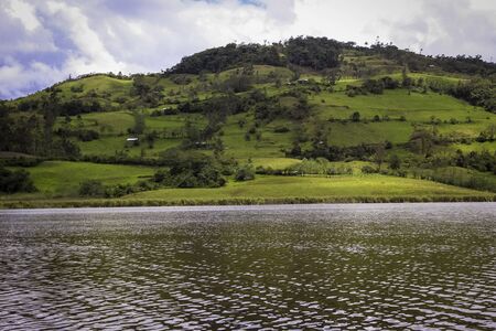 Landscape of colorful area and a lake in pomacochas, peru, with some houses separated each other and an interesting blue skyの写真素材