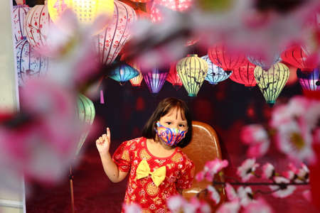 bogor, indonesia - february 23, 2021: a child wears a ceongsam Chinese dress with lanterns in the background on February 23 in the city of bogorのeditorial素材