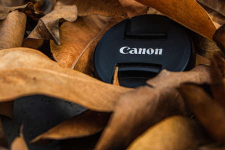 bogor,indonesia - 07 july 2021 : canon lens cap on a pile of dry leaves in the morning sunlightのeditorial素材