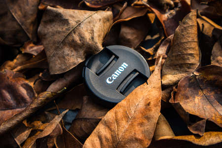 bogor,indonesia - 07 july 2021 : canon lens cap on a pile of dry leaves in the morning sunlightのeditorial素材