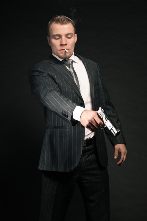 Man in suit shooting with gun  Smoking cigarette  Studio shot の写真素材